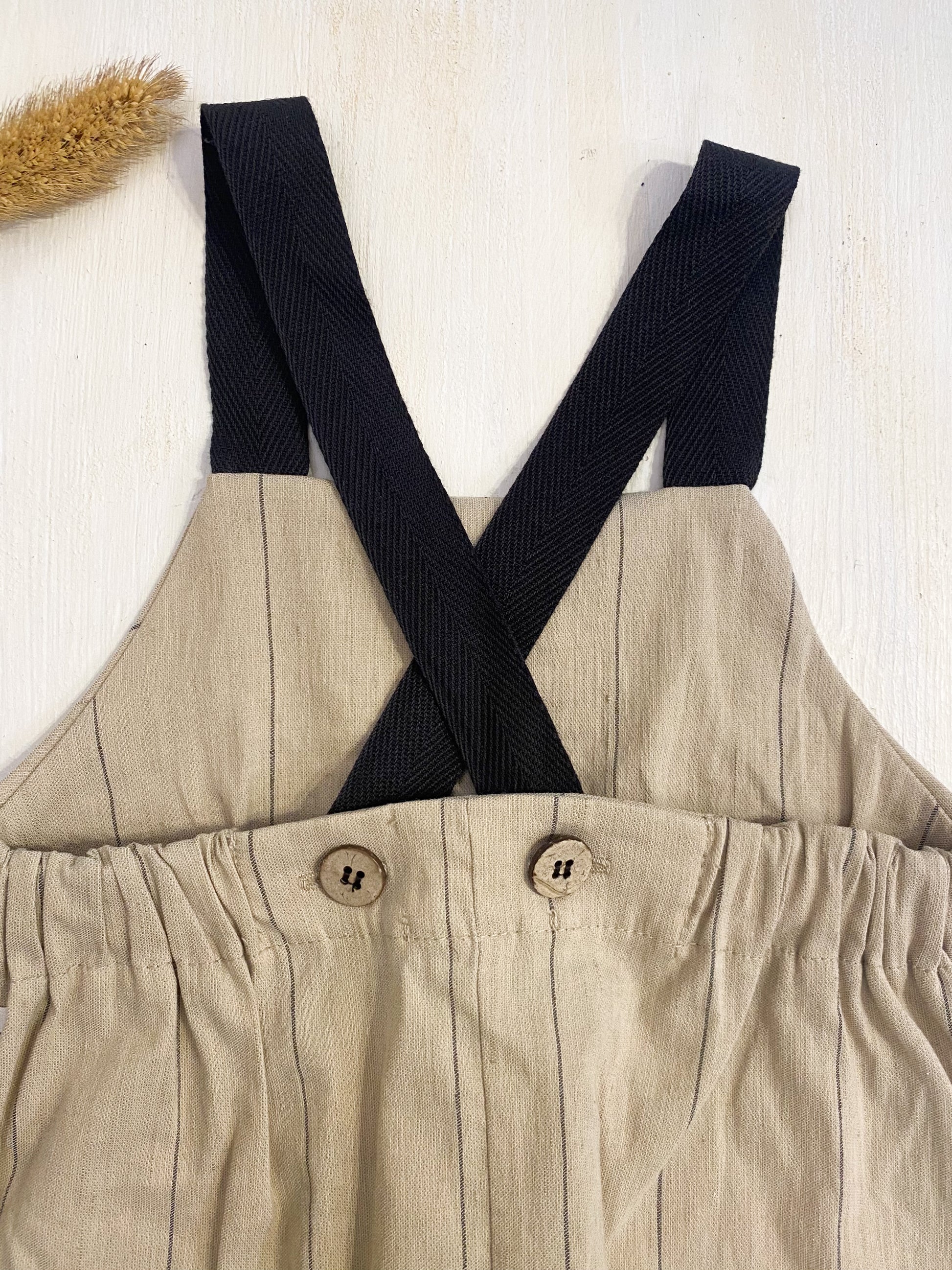 Salopette in cotone beige riga nera, bretelle nere.